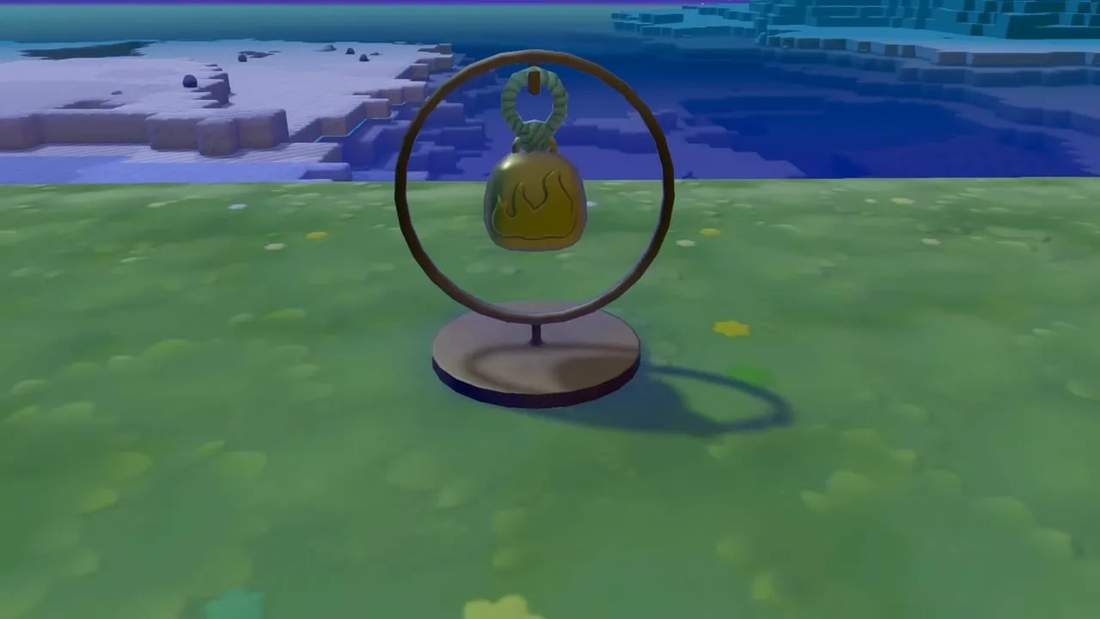 Clear Bell hanging in a ring stand on grassy terrain with ocean and cliffs in the background