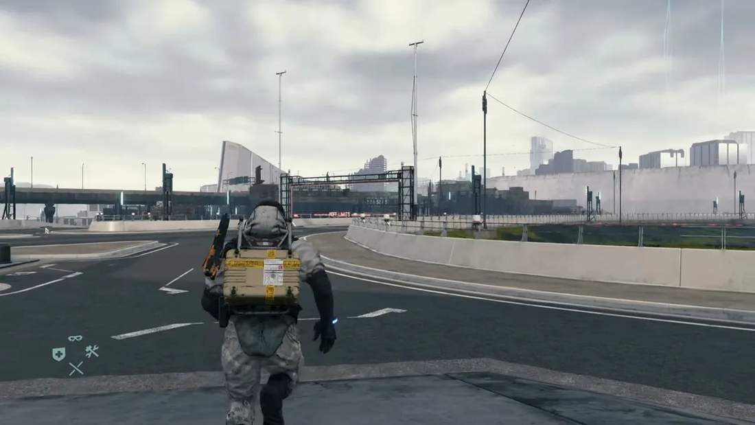 Player character walking down an empty highway carrying cargo with distant structures and mountains in Death Stranding.