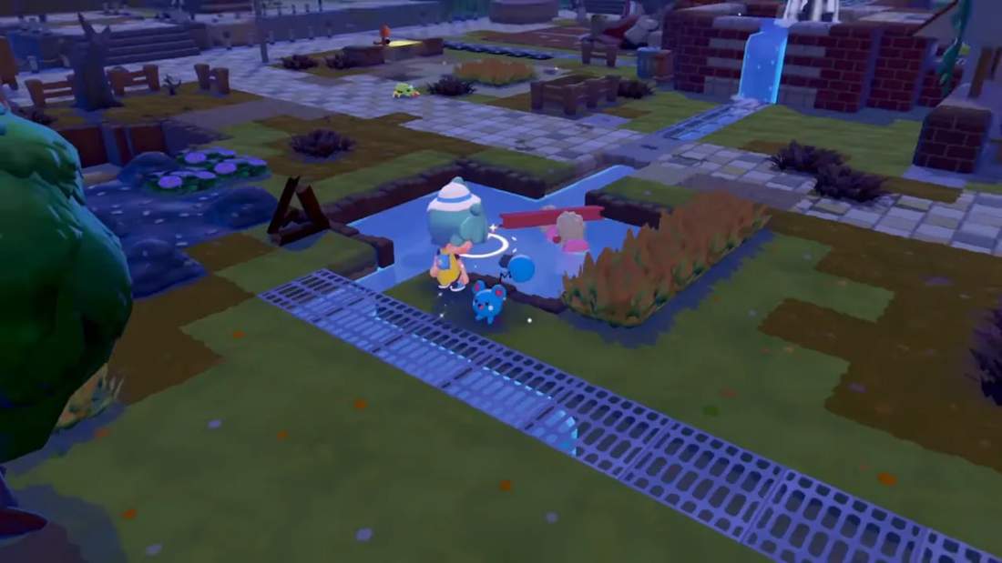 Wide view of a ruined-but-restored town area with pathways, a shallow pool with Pok&eacute;mon, patchy grass and rebuilt walkways.