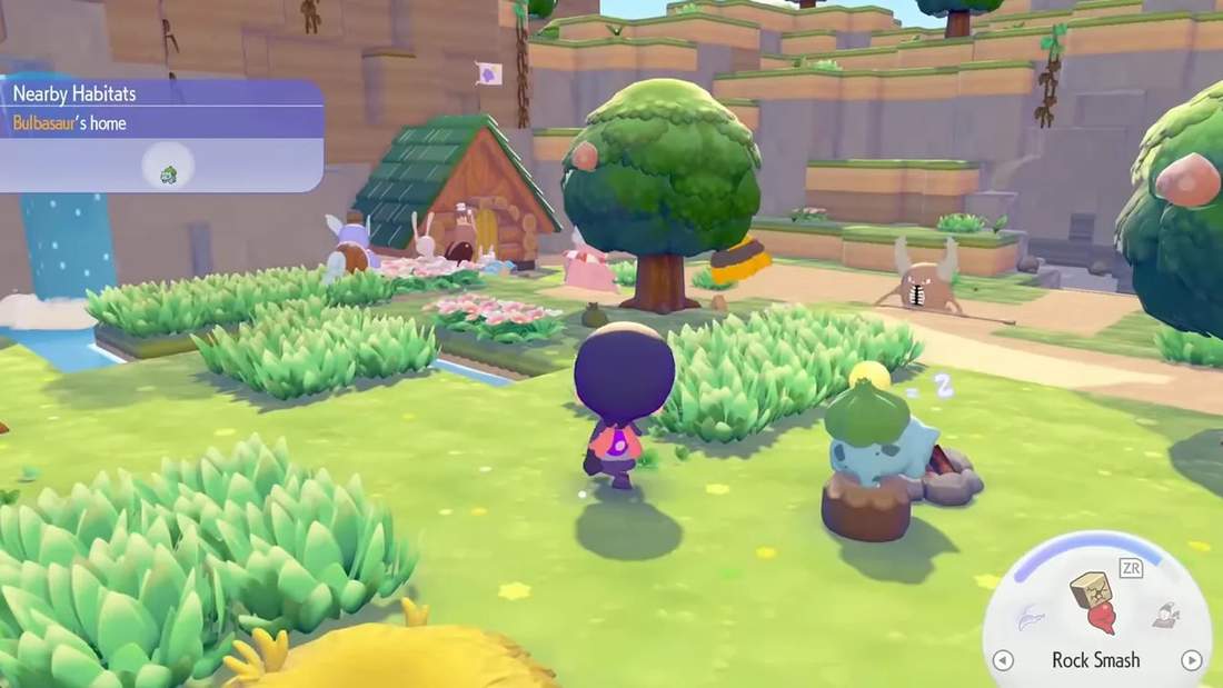 Overhead view of a starter island habitat showing grass patches, flower beds, a tree, a small house and a sleeping Bulbasaur