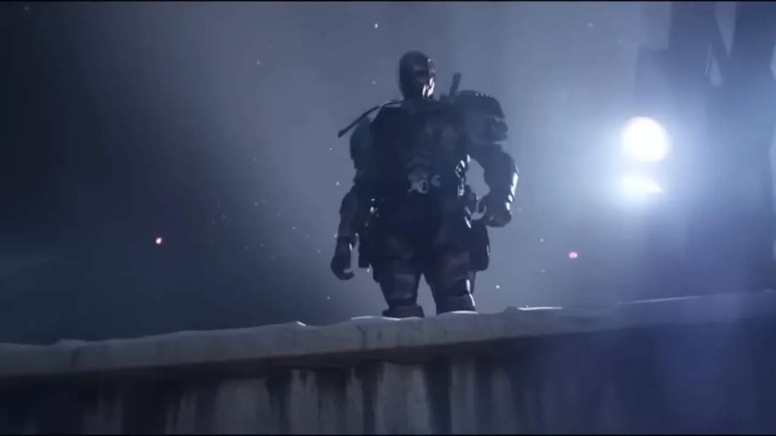 Batman standing on a ledge in dramatic blue lighting with falling particles