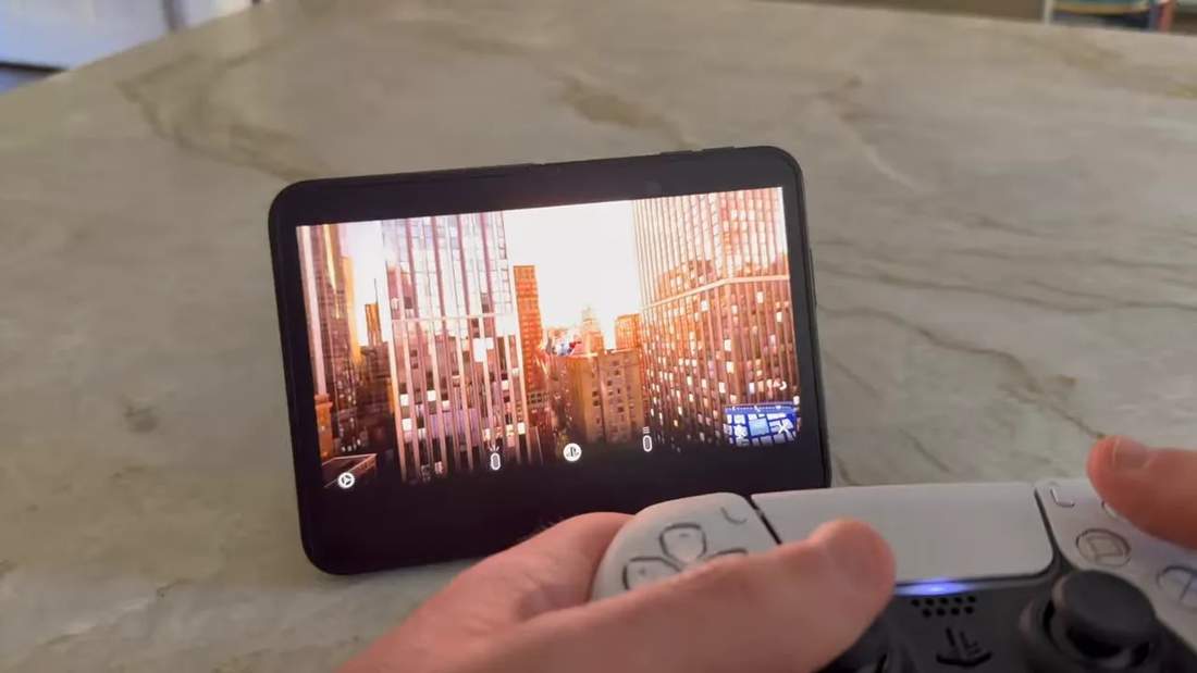 Unfolded phone showing Spider-Man gameplay with a white PlayStation controller held in the foreground